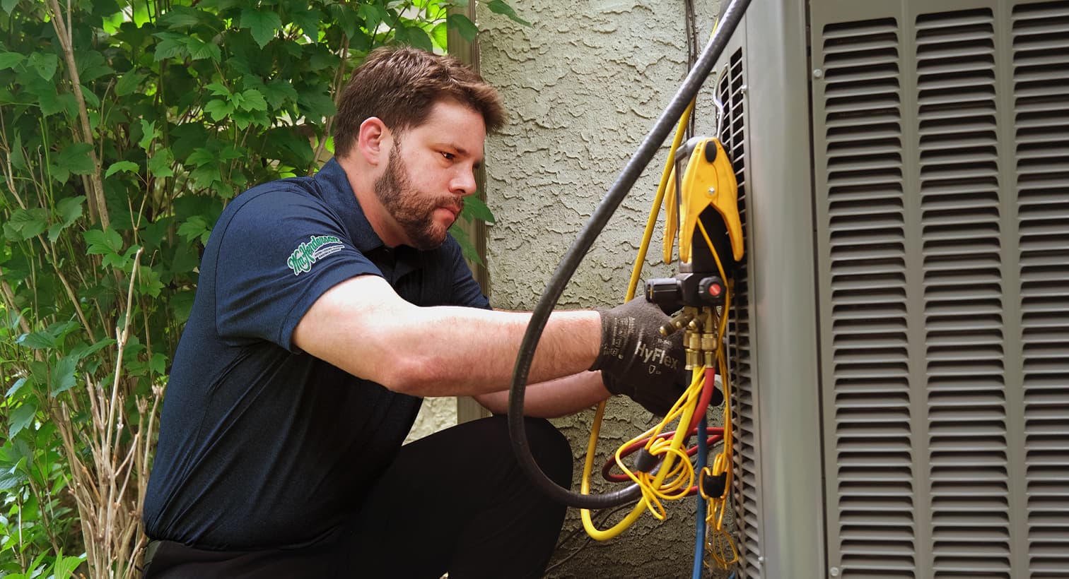 A professional Wm Henderson HVAC technician inspecting an outdoor central air conditioning unit to provide residential AC repair and diagnostic services.