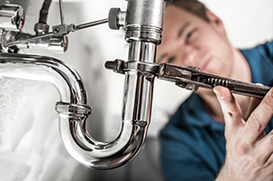 Plumber doing some work under the sink. Tightening siphon.